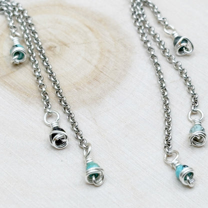 Silver earrings with turquoise beads on a light wooden surface