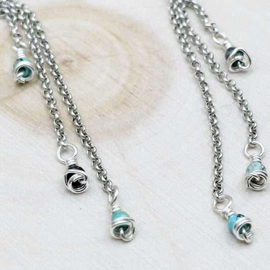 Silver earrings with turquoise beads on a light wooden surface