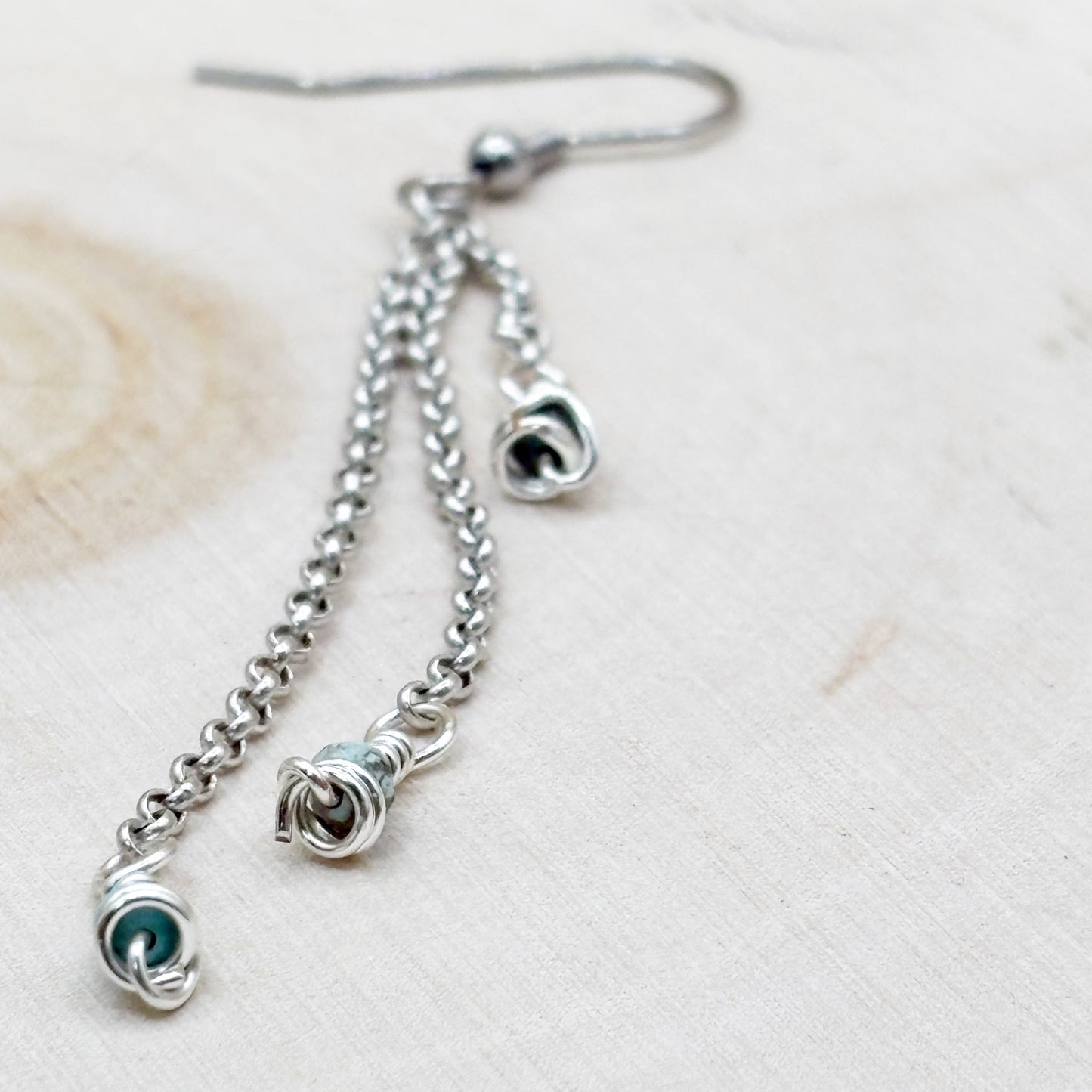 Silver chain earring with elegant design on a light wood background