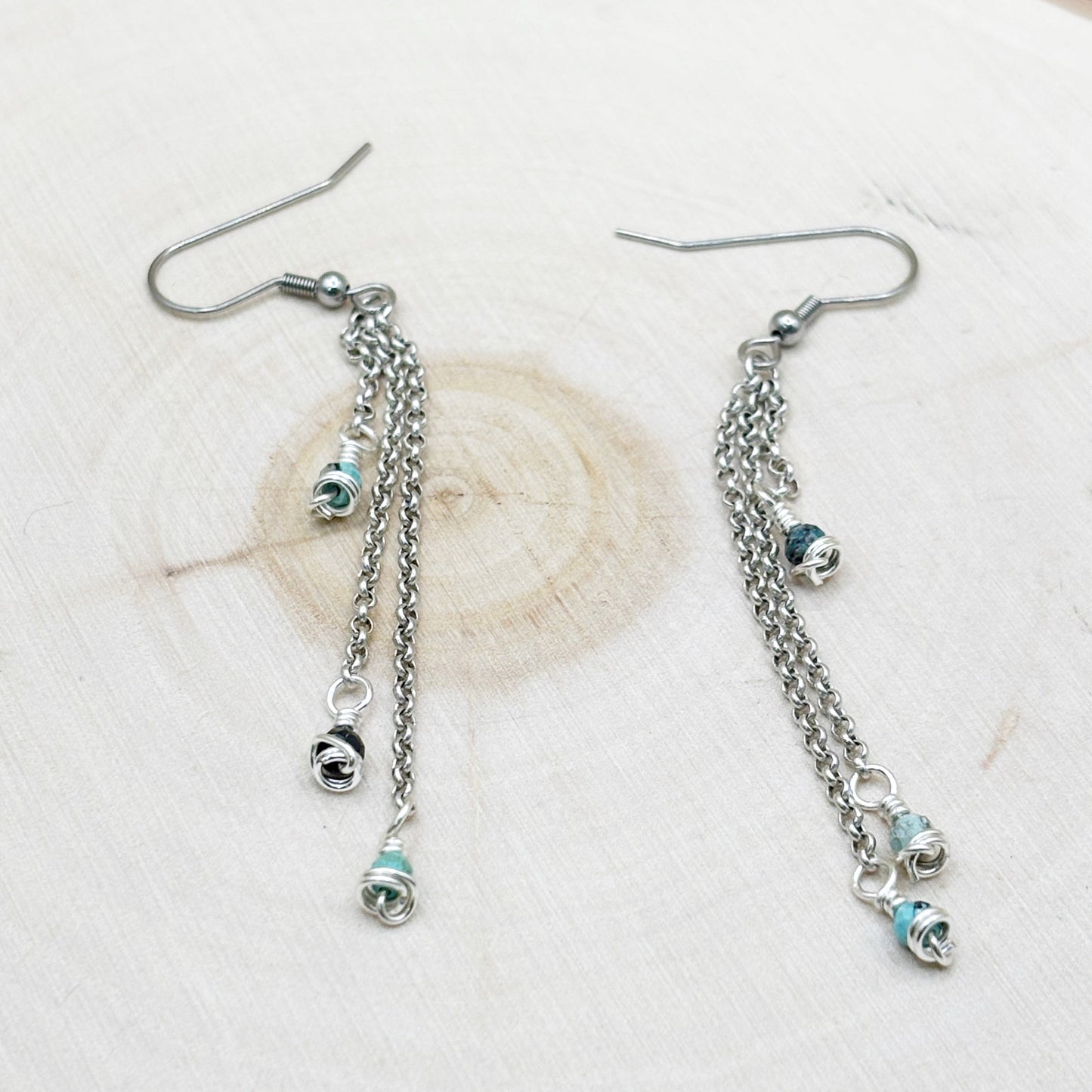 Silver chain earrings with small round charms on a light background