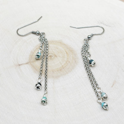 Silver chain earrings with small round charms on a light background