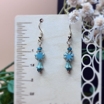 turquoise floral earrings with gold tone wire hanging on a wooden stand to show case measurement 