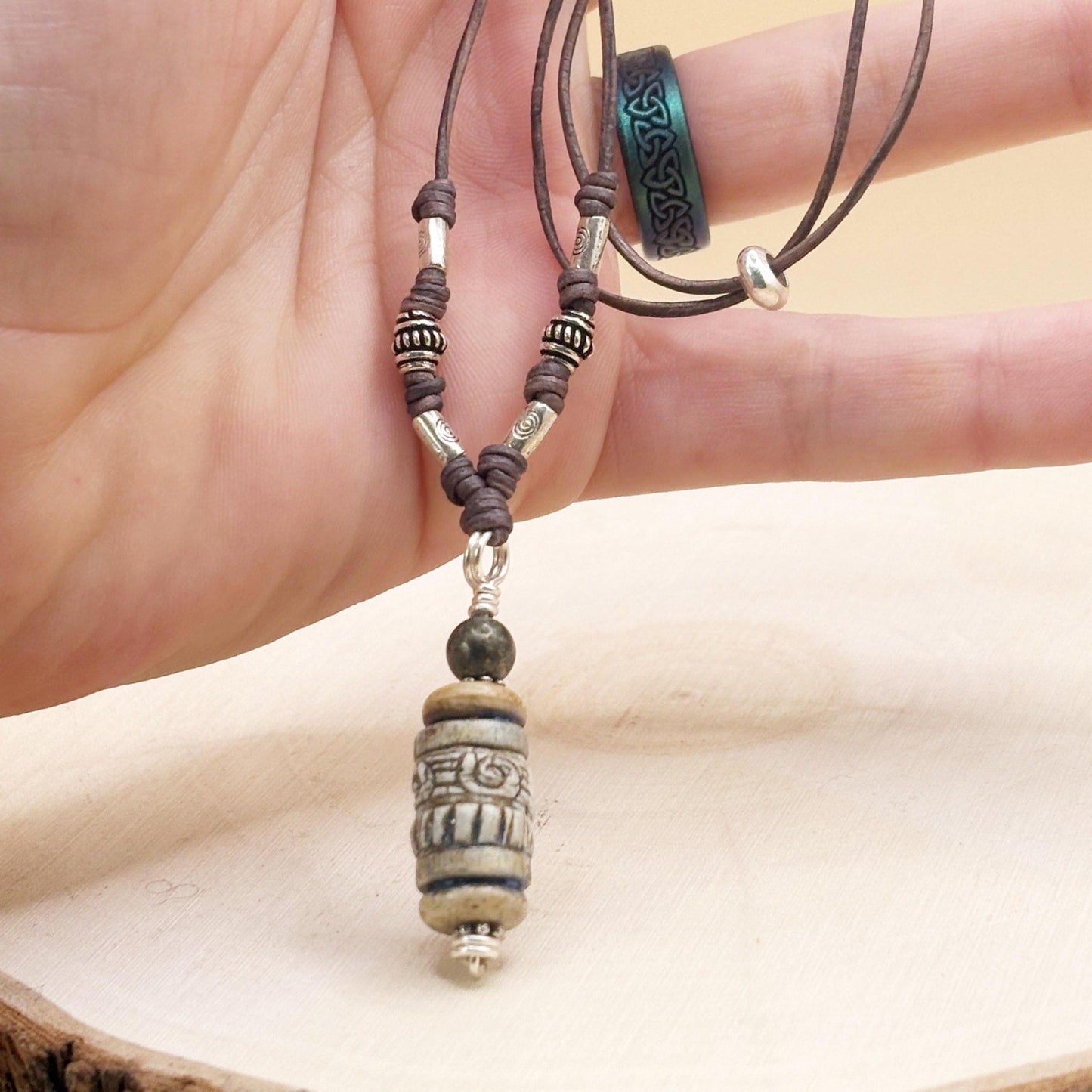 Close-up of a hand holding a beaded necklace with a large pendant.