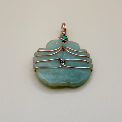Jade pendant with copper wire wrapping on a light gray background