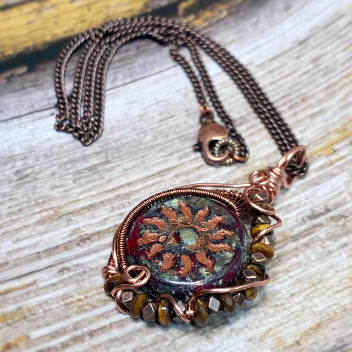 Wire wrap pendant in copper with a sunburst red glass coin with tigers eye beads on an 18 inch chain