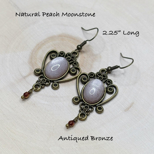 Pair of earrings with peach moonstone stones and anted bronze setting on a light background-p