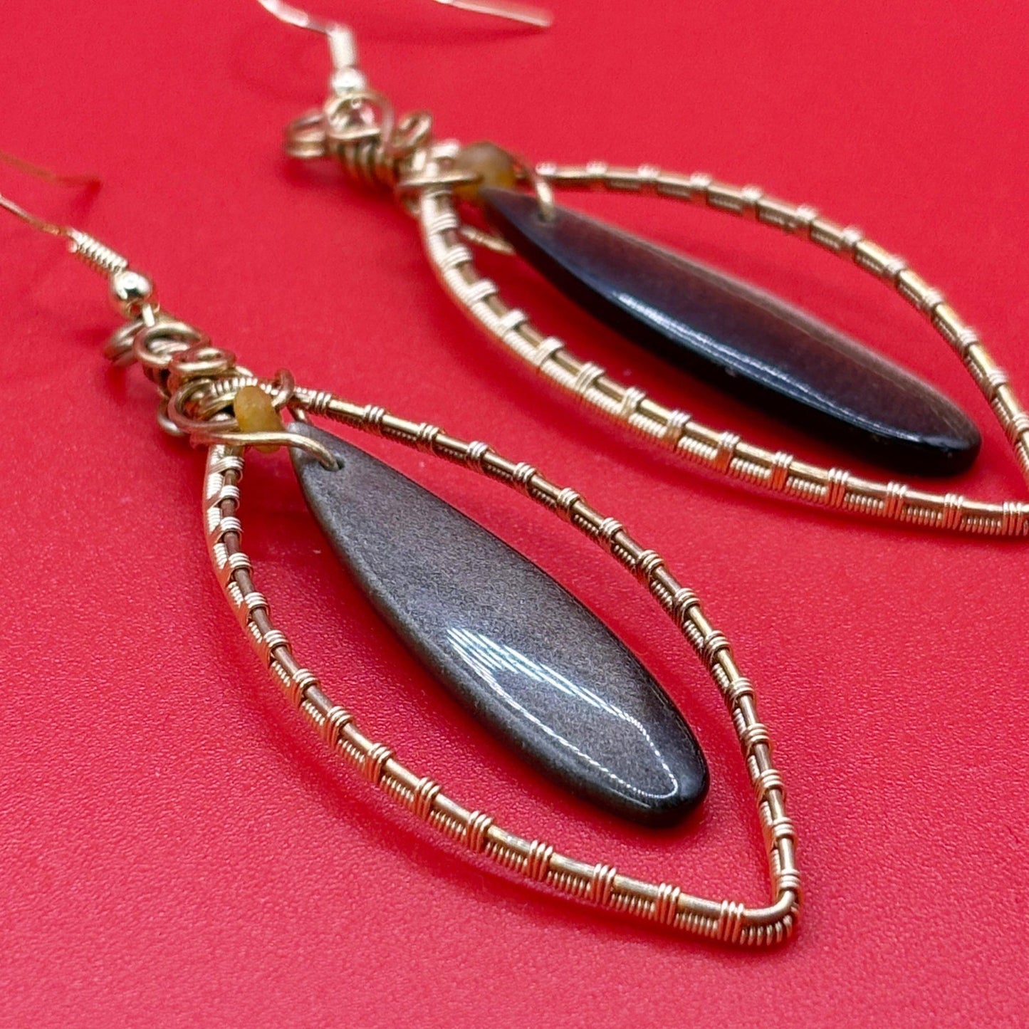 Gold and black teardrop earrings on a red background