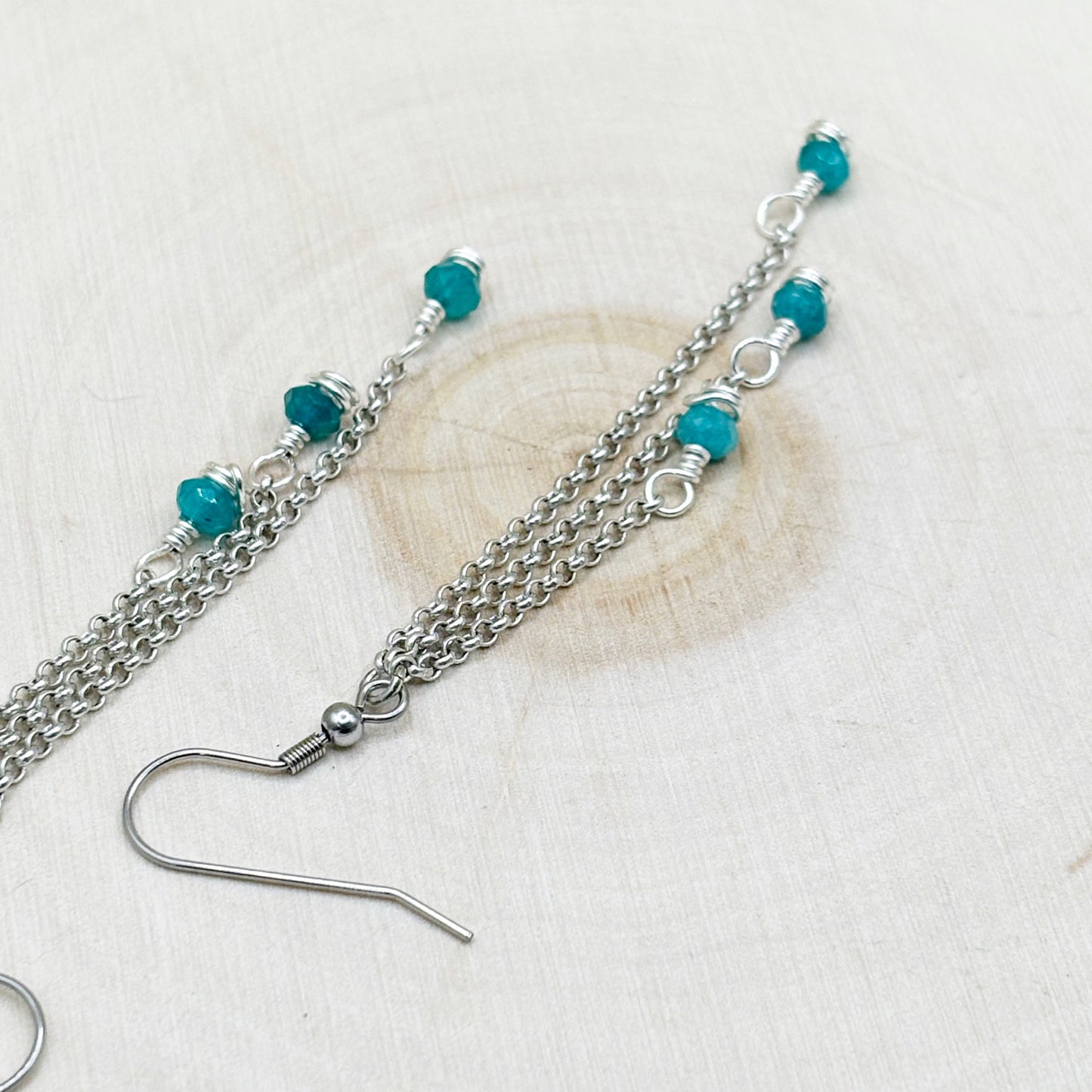 Silver chain earring with turquoise beads on a light background