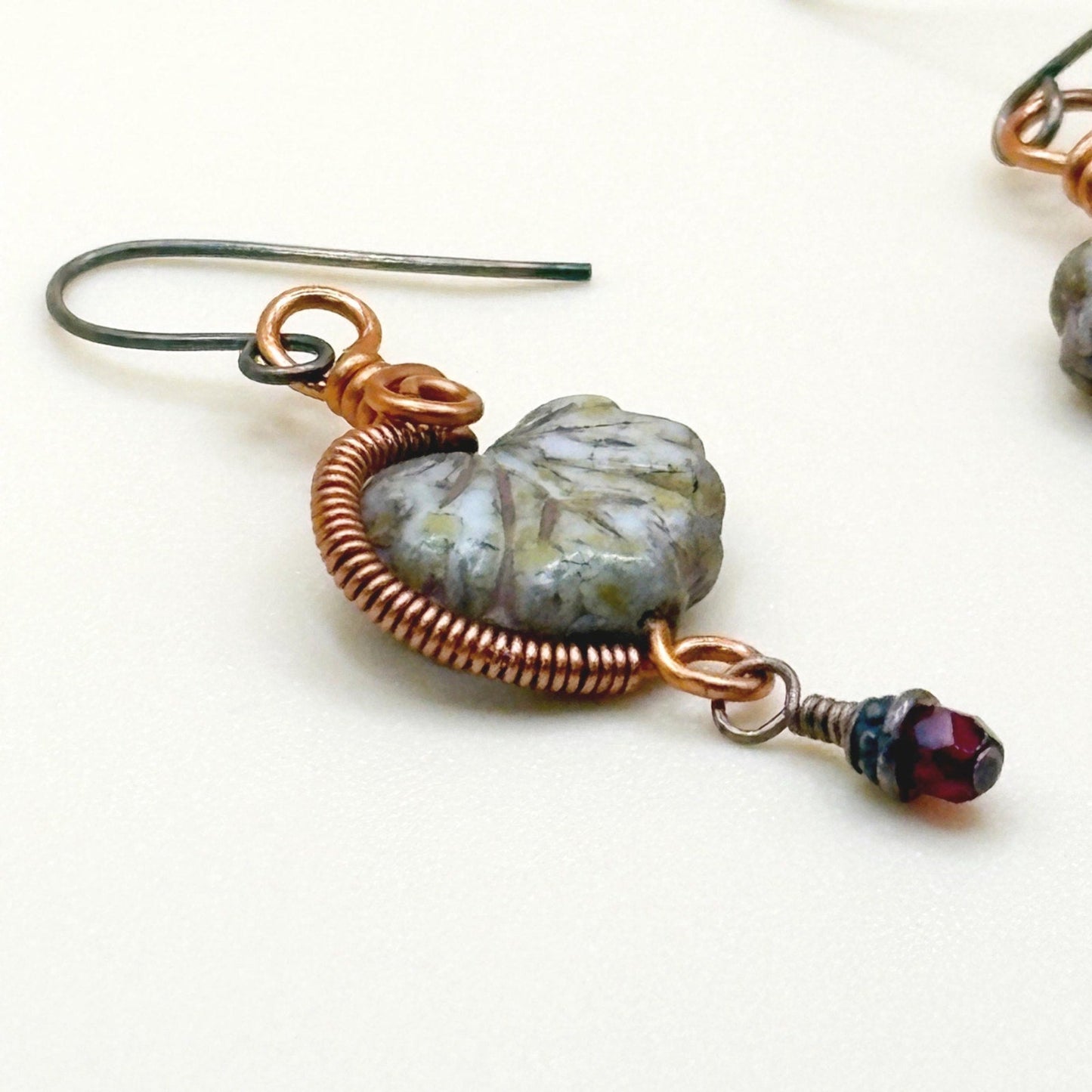 Earrings with glass maple leaf and copper wire design on a white background