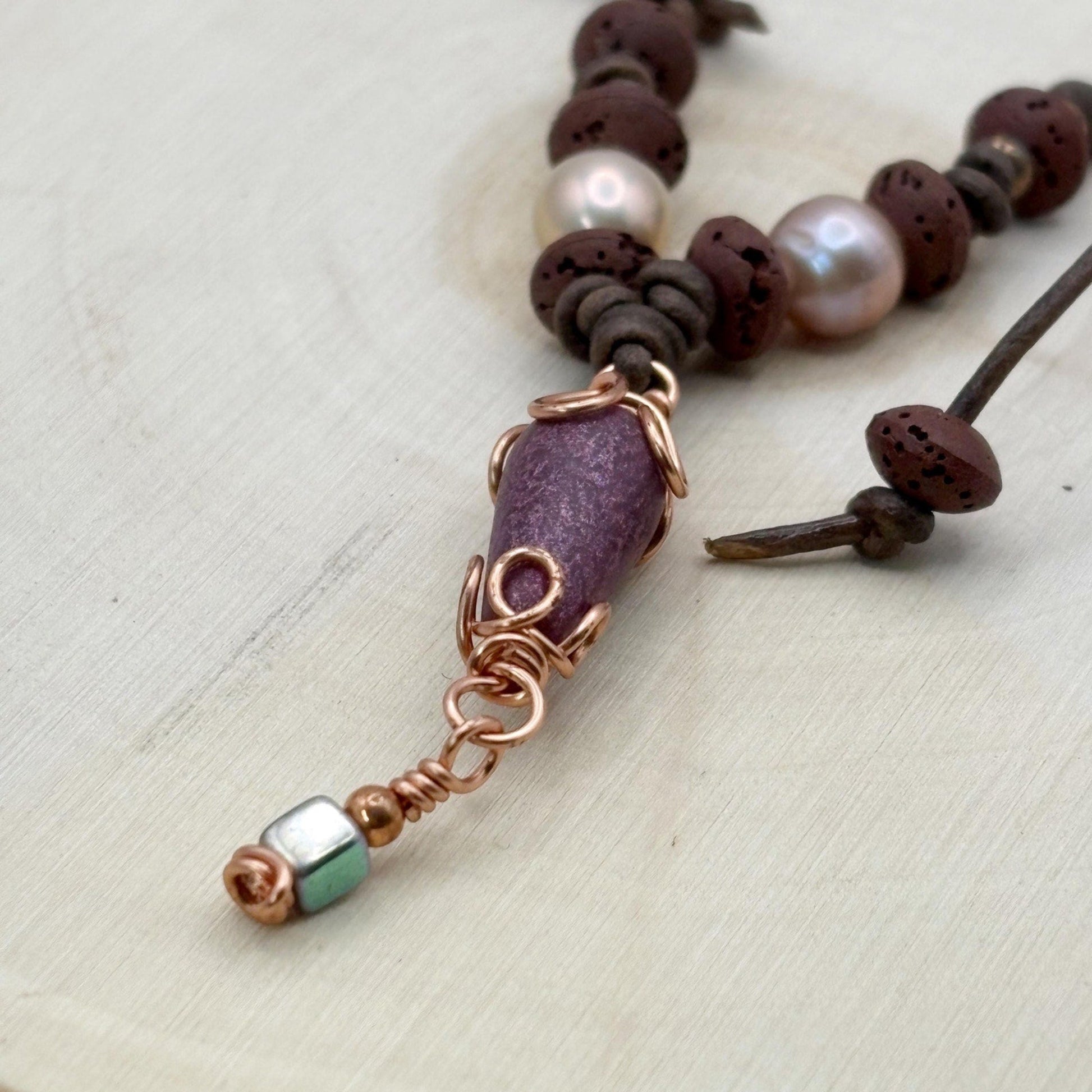 Necklace with brown beads and a purple pendant on a light background