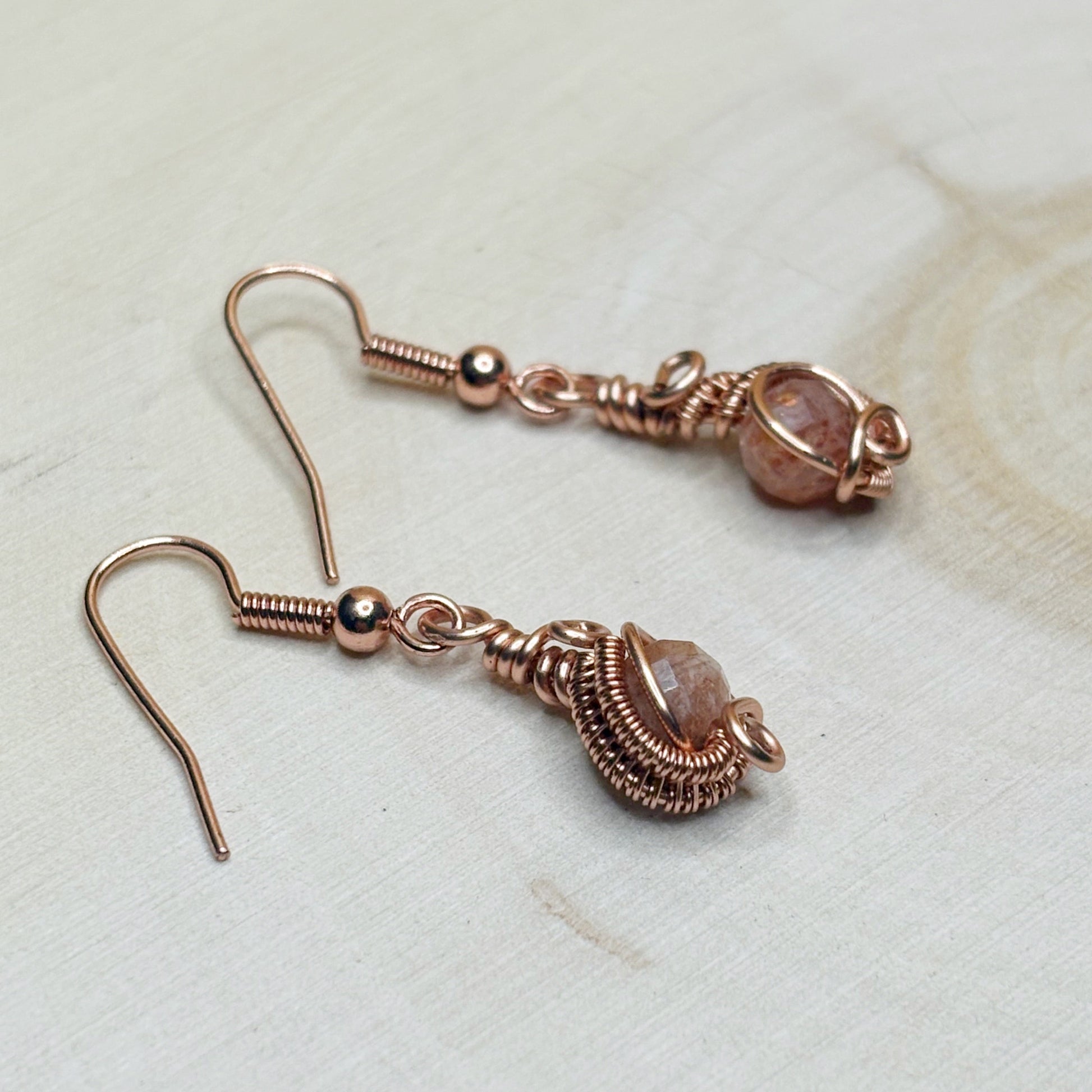 Copper wire wrap earrings with gemstones on a light background