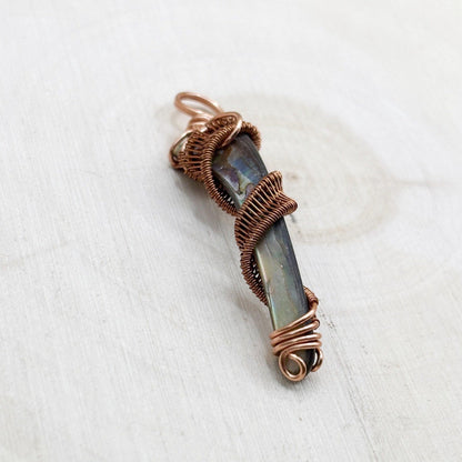 Copper-wrapped abalone shell pendant on a white background