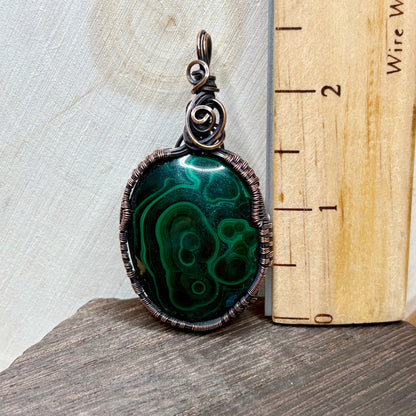 Copper jewelry with green stone on wood background