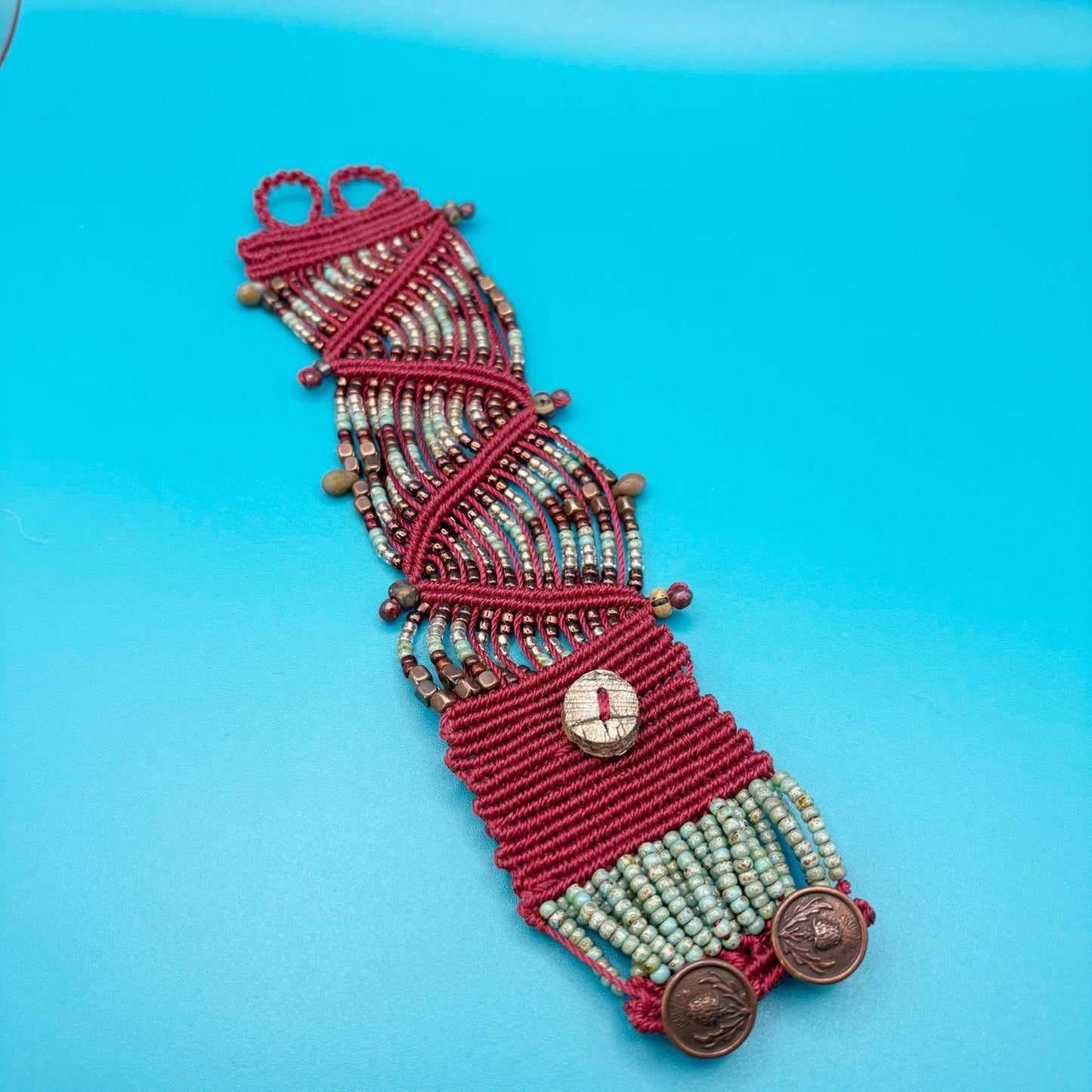Red beaded bracelet with decorative elements on a blue background