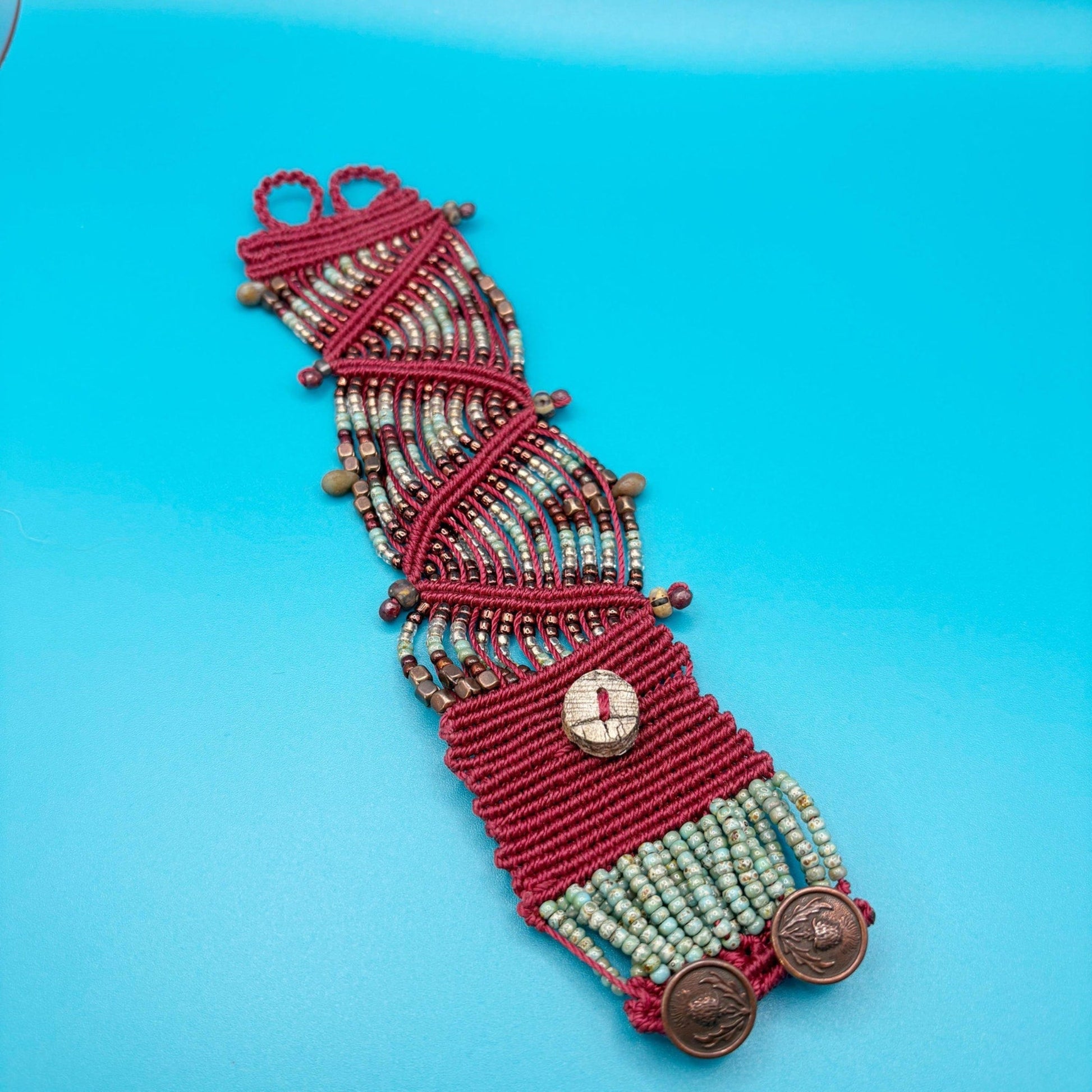 Red beaded bracelet with decorative elements on a blue background