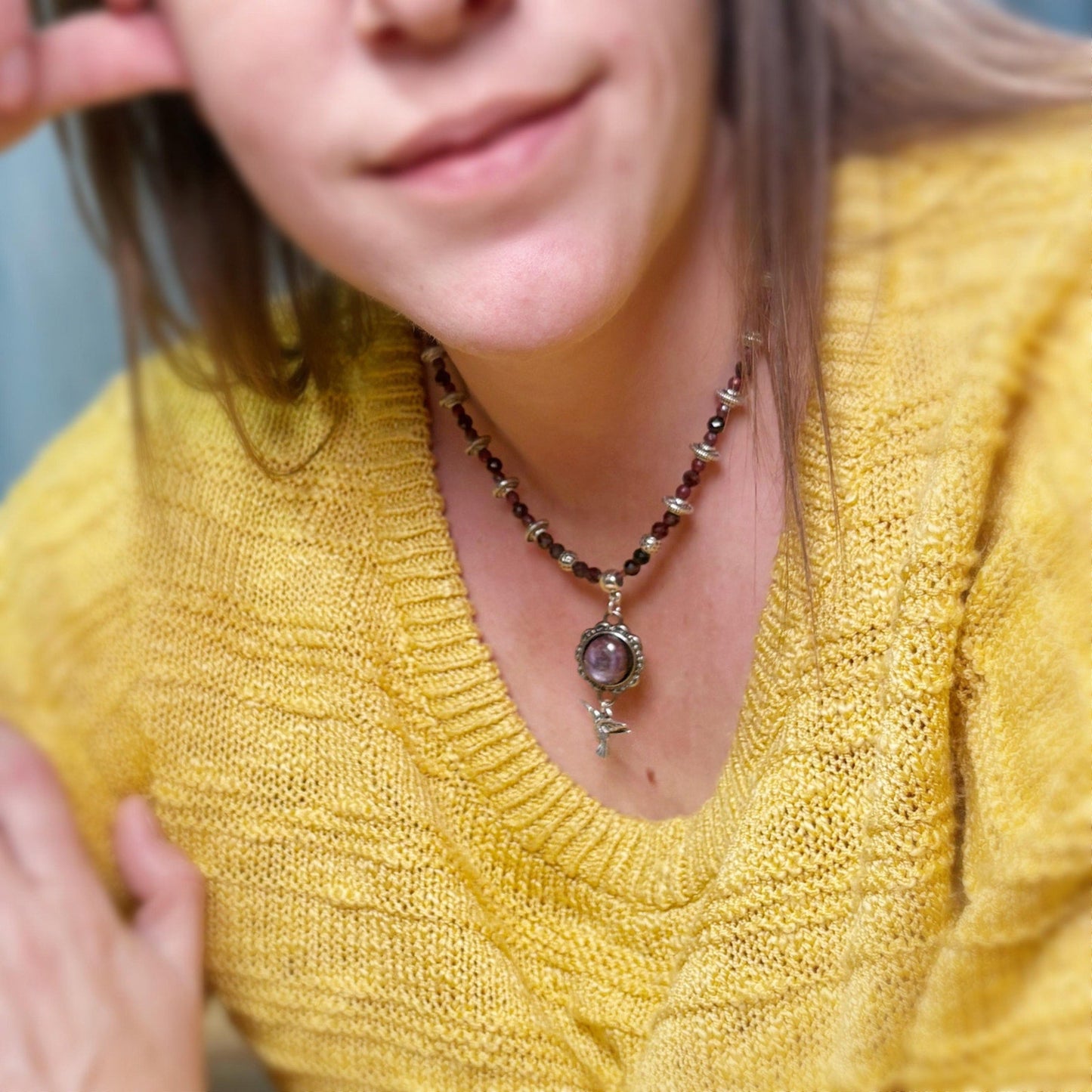 Person wearing a yellow sweater and a necklace with a pendant.