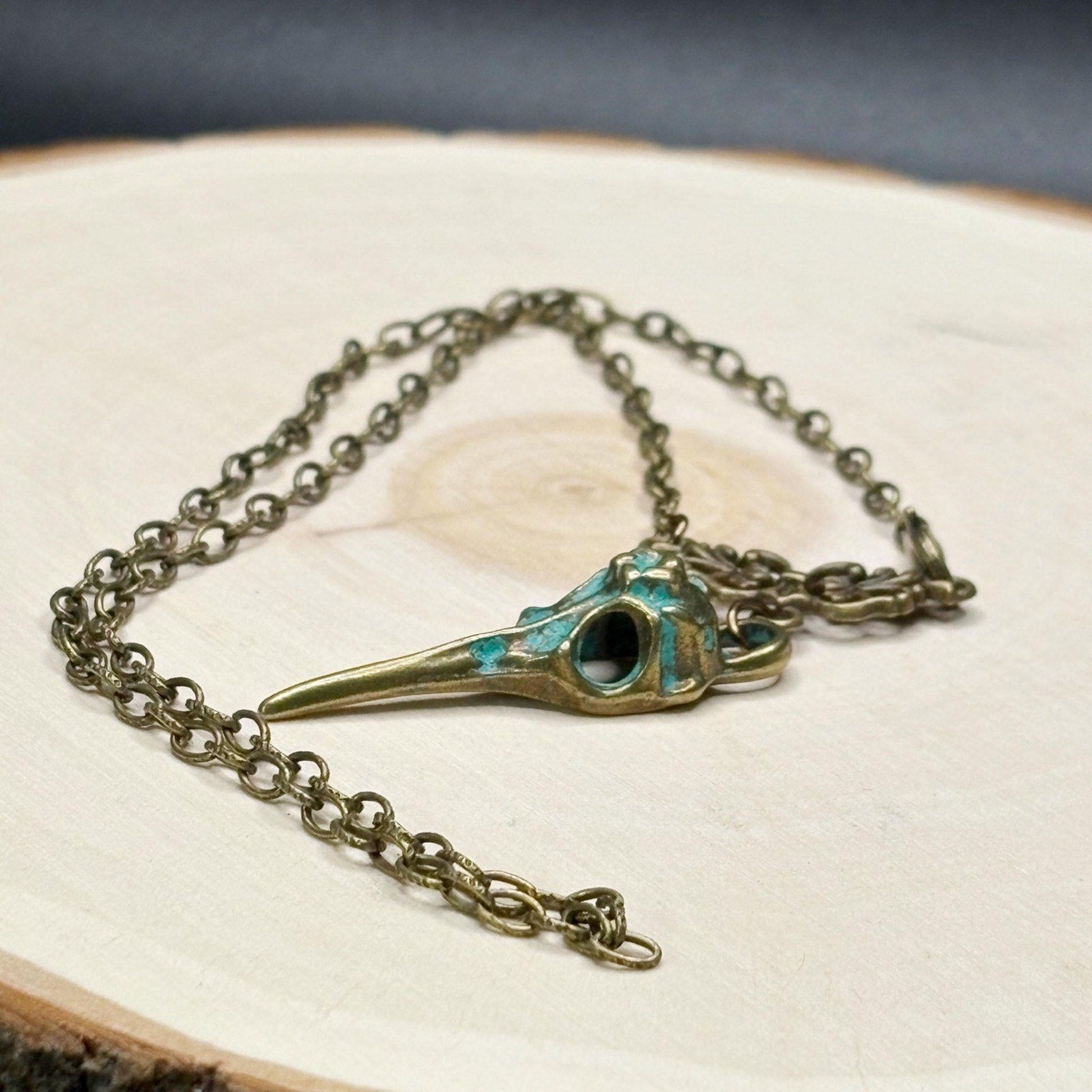 Necklace with a bird skull pendant on a textured surface