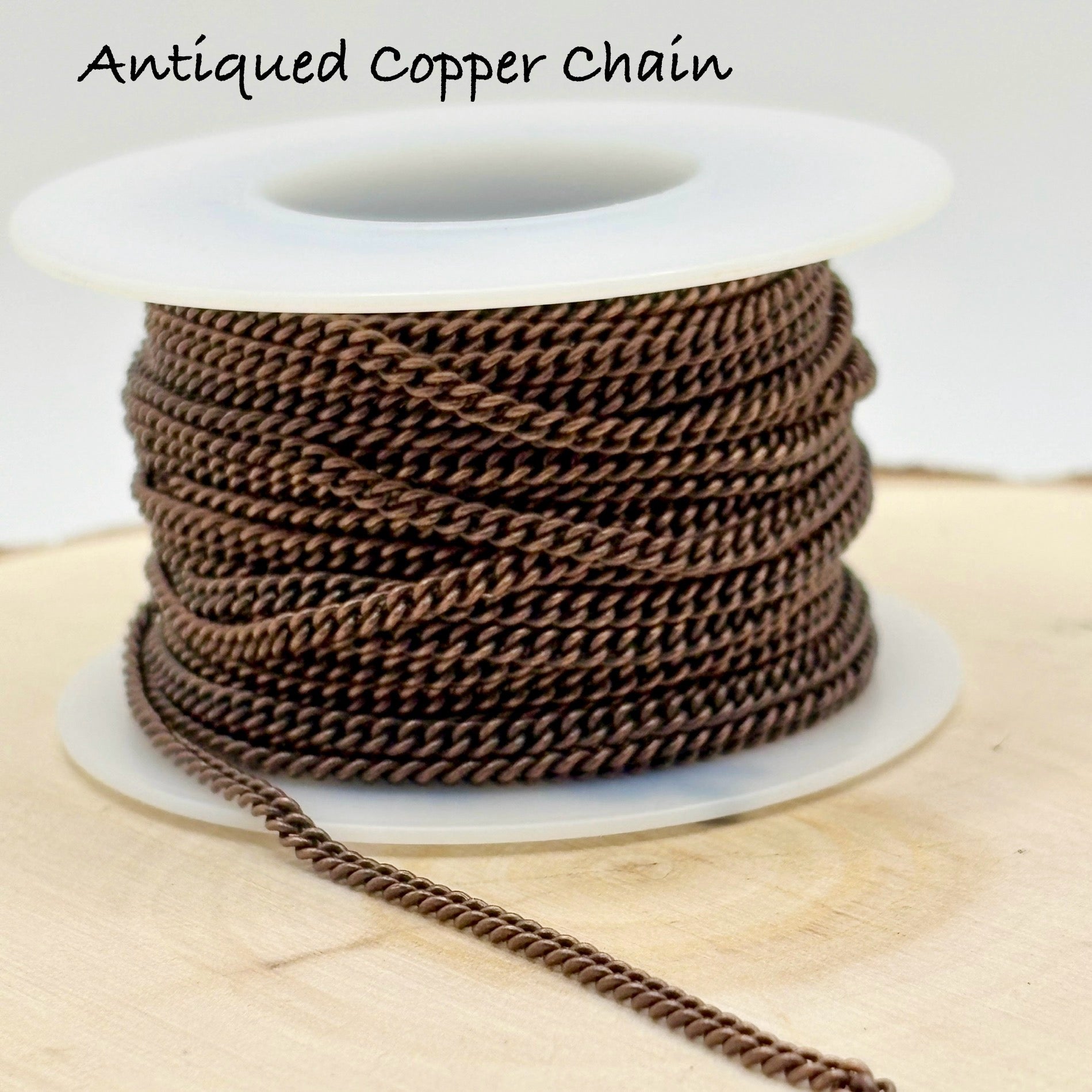 Spool of antique copper chain on a wooden surface with text 'Antiqued Copper Chain'.