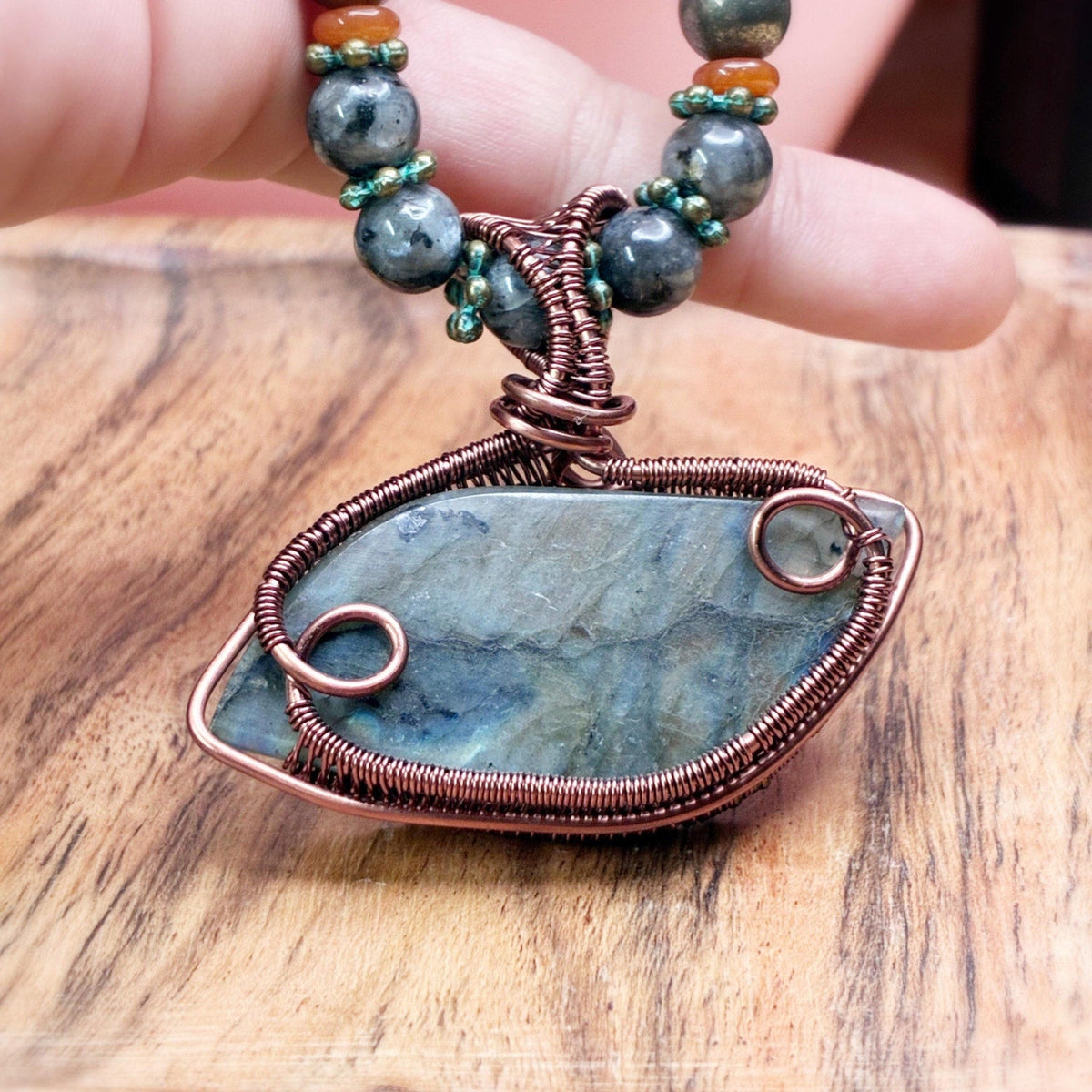 Hand holding a wire wrap pendant featuring the elegant back side of the piece