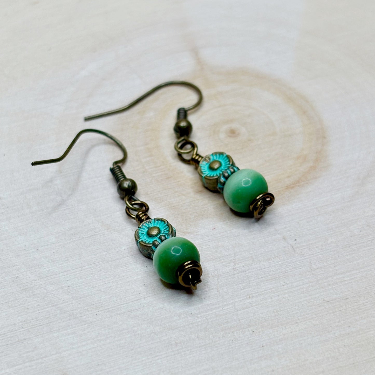 Pair of green and bronze earrings on a light background