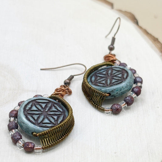 Pair of earrings with blue circular designs and beaded accents on a white background