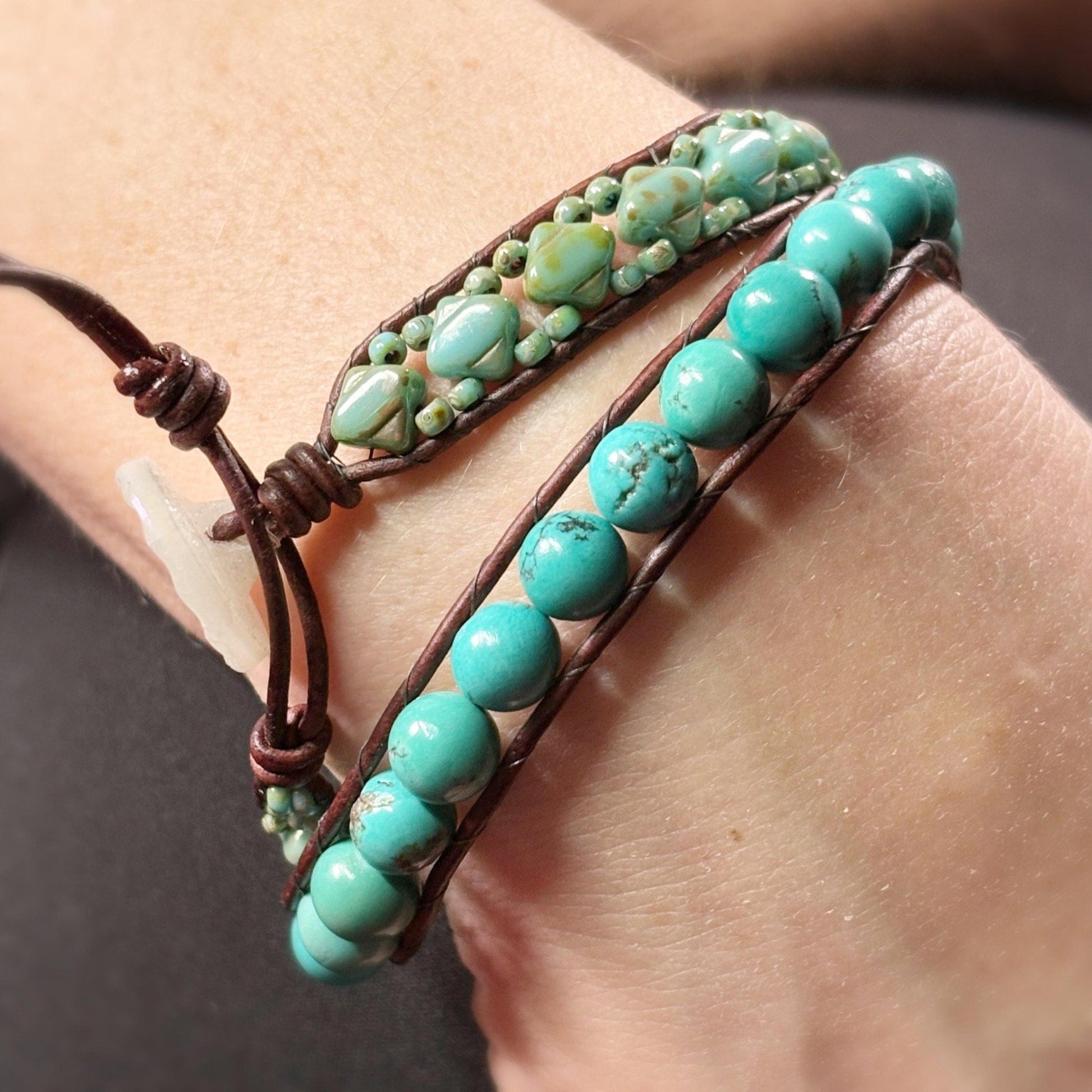 Turquoise beaded bracelet with brown leather strap on wrist against a neutral background