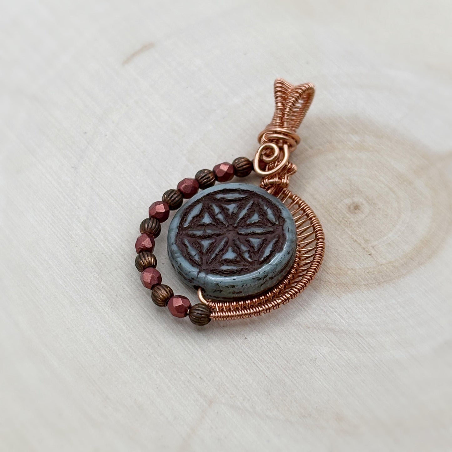 Copper and glass pendant on a light wooden surface