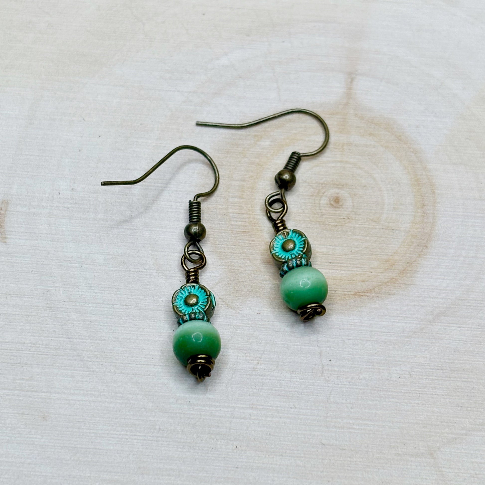 Pair of green beaded earrings on a light wooden surface