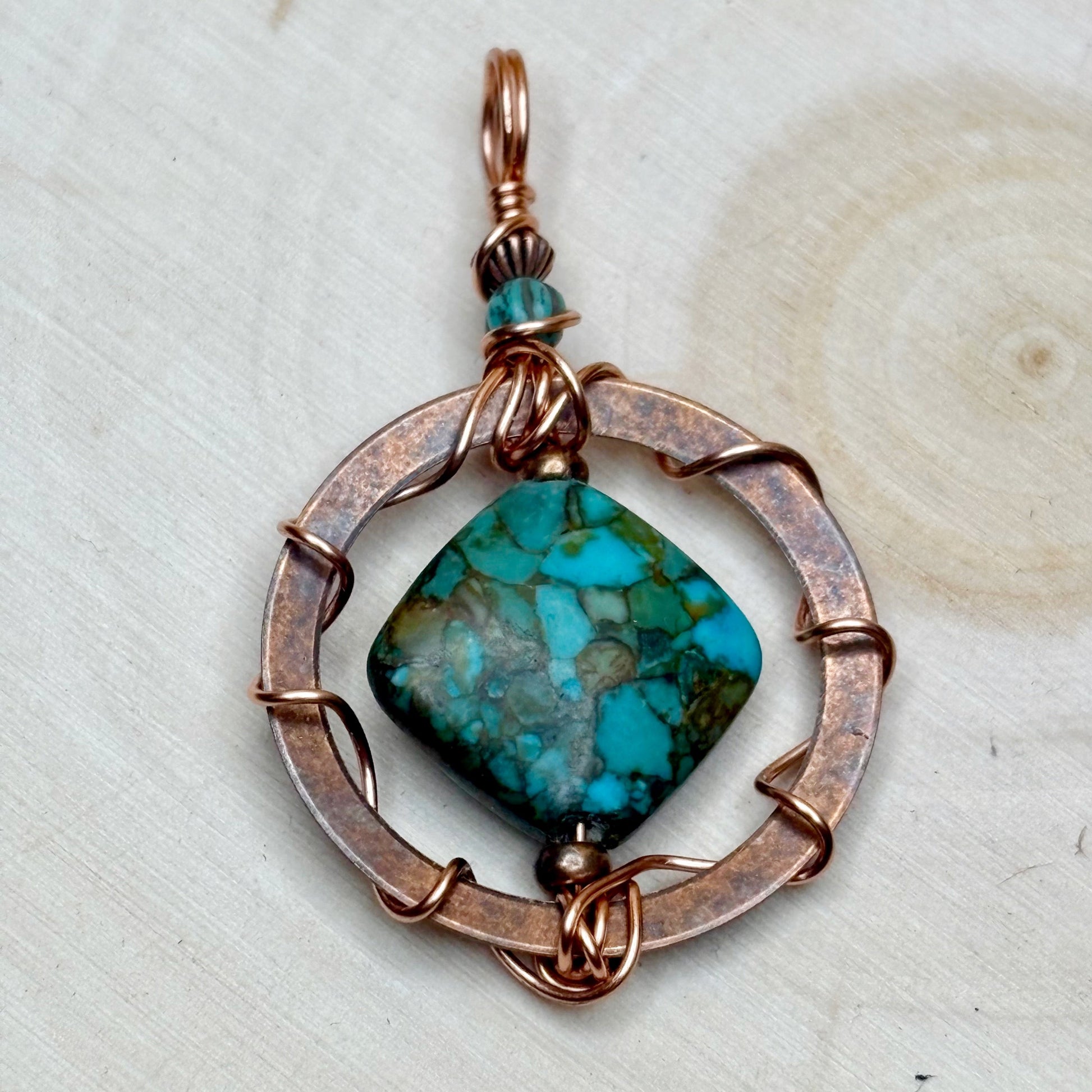 Copper pendant with turquoise stone on a light background