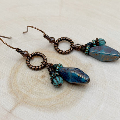 Pair of earrings with blue and brown beads on a wooden surface