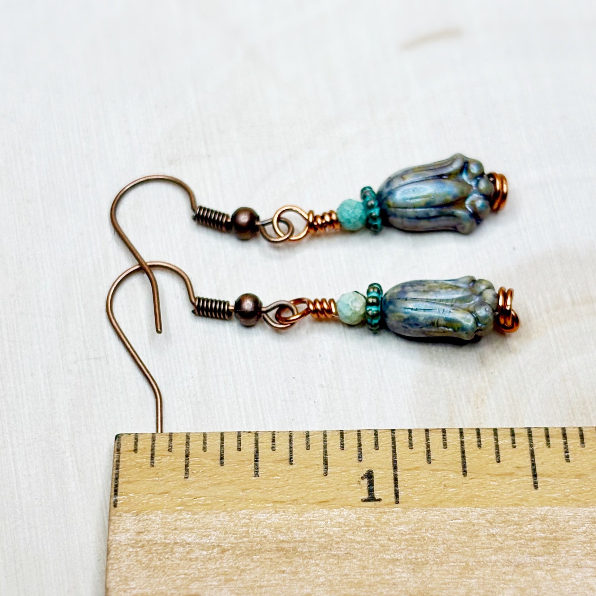 Pair of earrings with blue and green beads on a wooden ruler for scale.