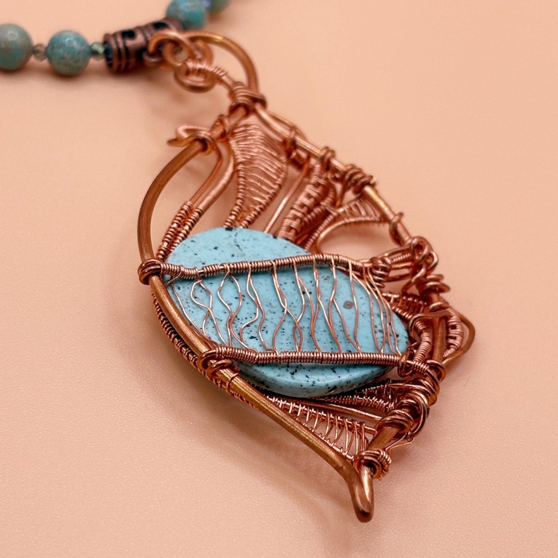Necklace with a copper pendant featuring a blue stone on a beige background