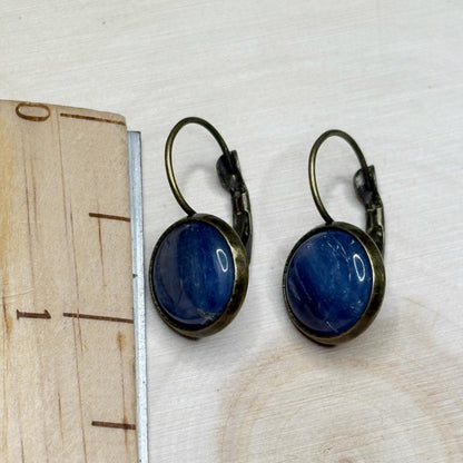 Pair of blue earrings with bronze hooks on a wooden surface with a ruler for scale.