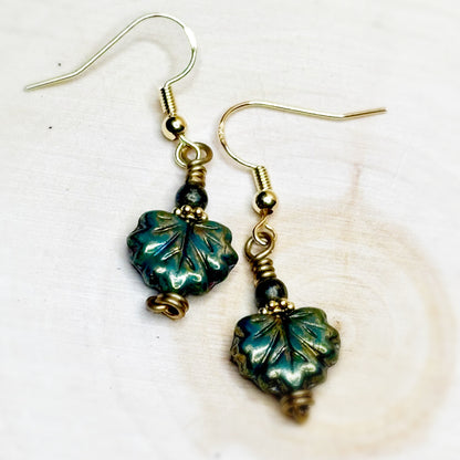 Pair of earrings with green leaf-shaped beads on a white background