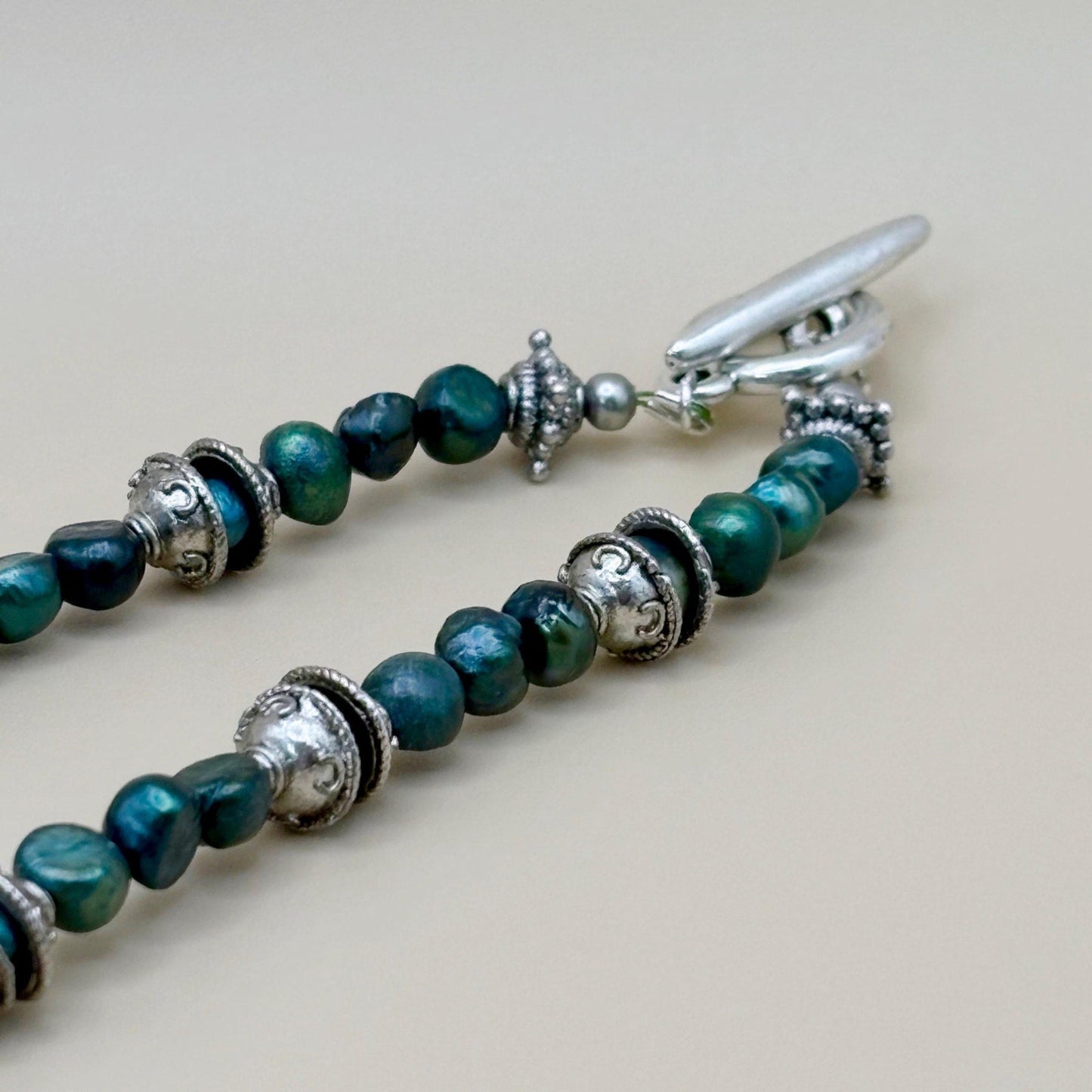 Necklace with green beads and silver clasp on a light background
