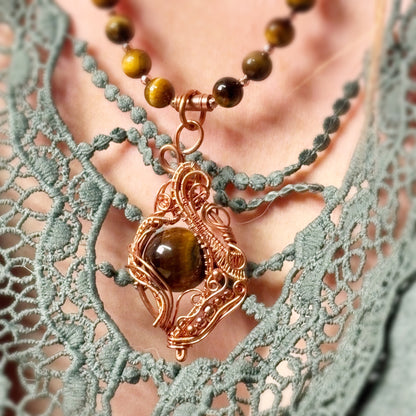 Necklace with a brown pendant on a person wearing a green lace garment