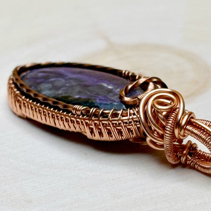 Copper-wrapped pendant with a colorful stone on a white background
