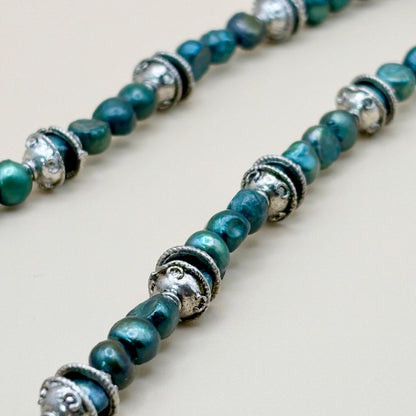 Necklace with green beads and silver accents on a light background