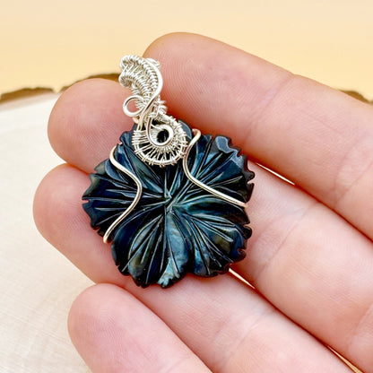 Decorative pendant held between fingers with a neutral background
