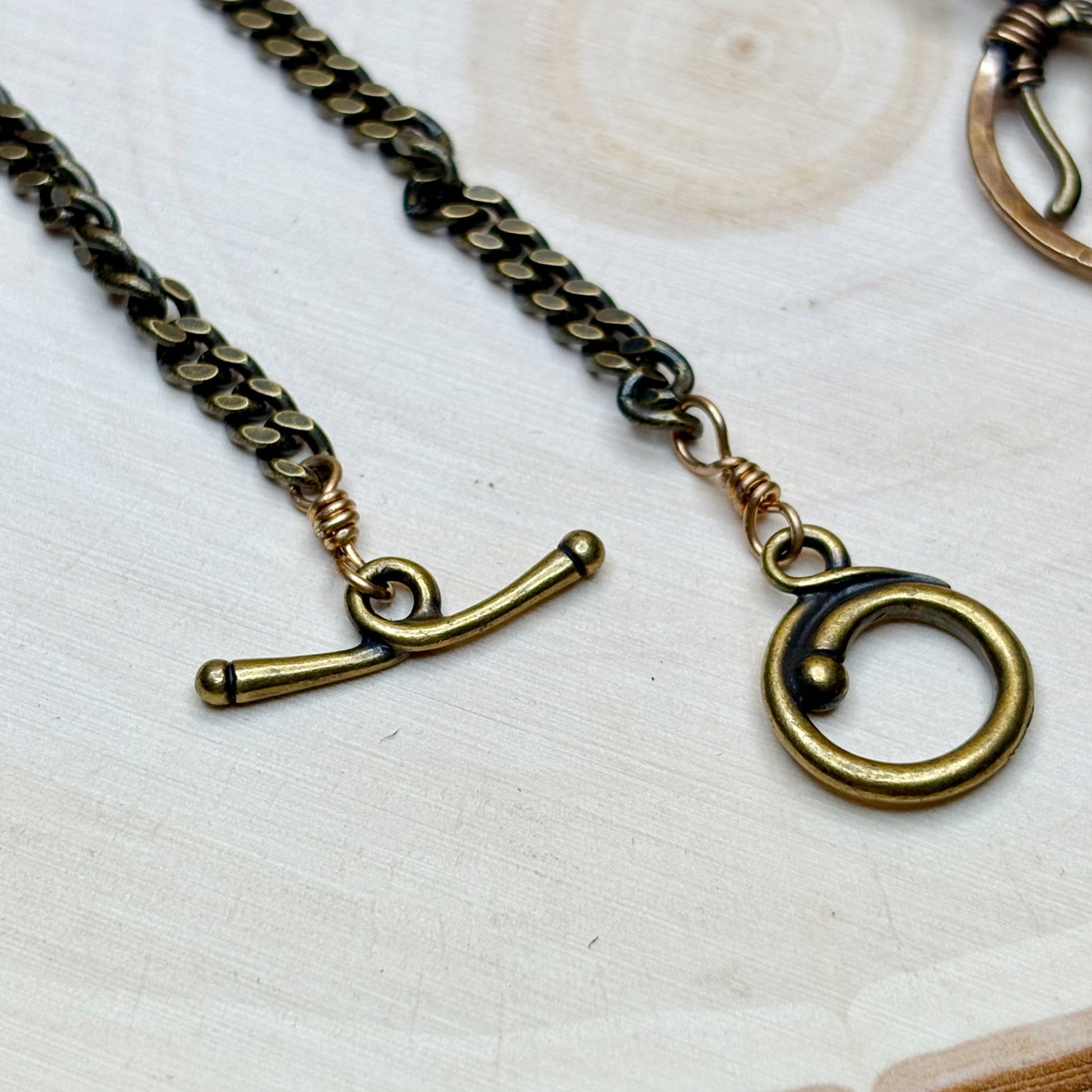Brass chain necklace with clasp and pendant on a light background
