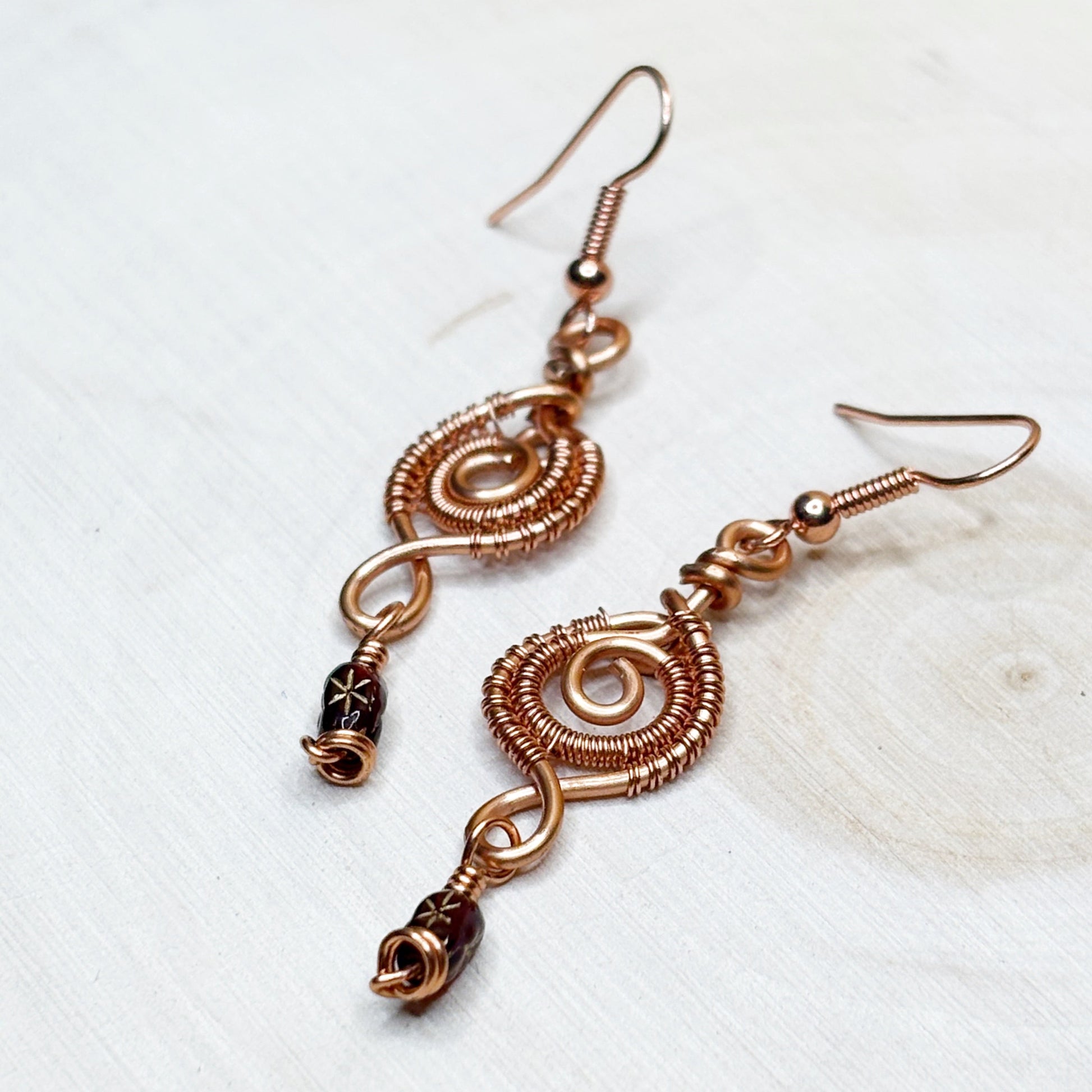 Copper wire-wrapped earrings on a light background