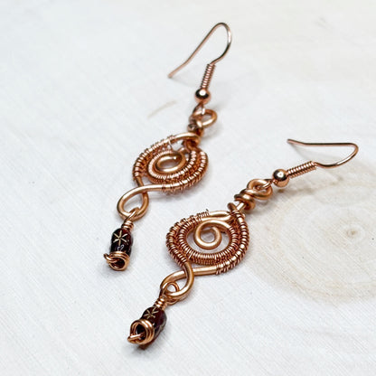 Copper wire-wrapped earrings on a light background
