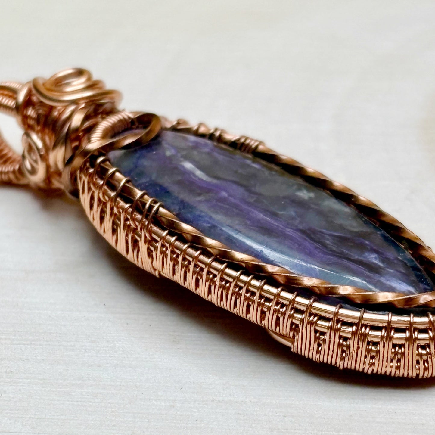Charoite wire wrap pendant in tarnish resistant copper on wooden background